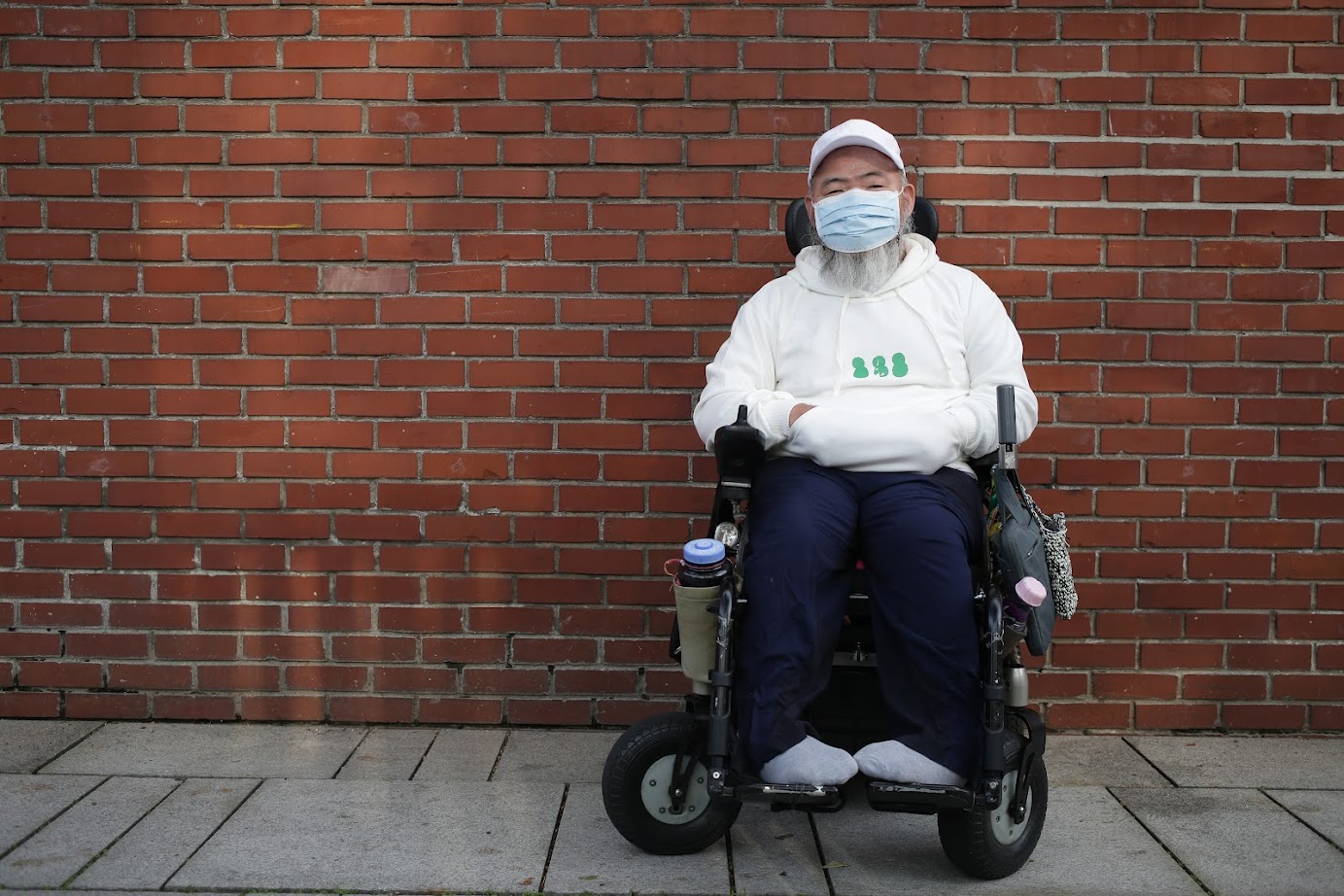 녹색 눈사람(흰색 후드) 을 입고 휠체어에 앉아 포즈를 취한 노들장애인야학 교장선생님