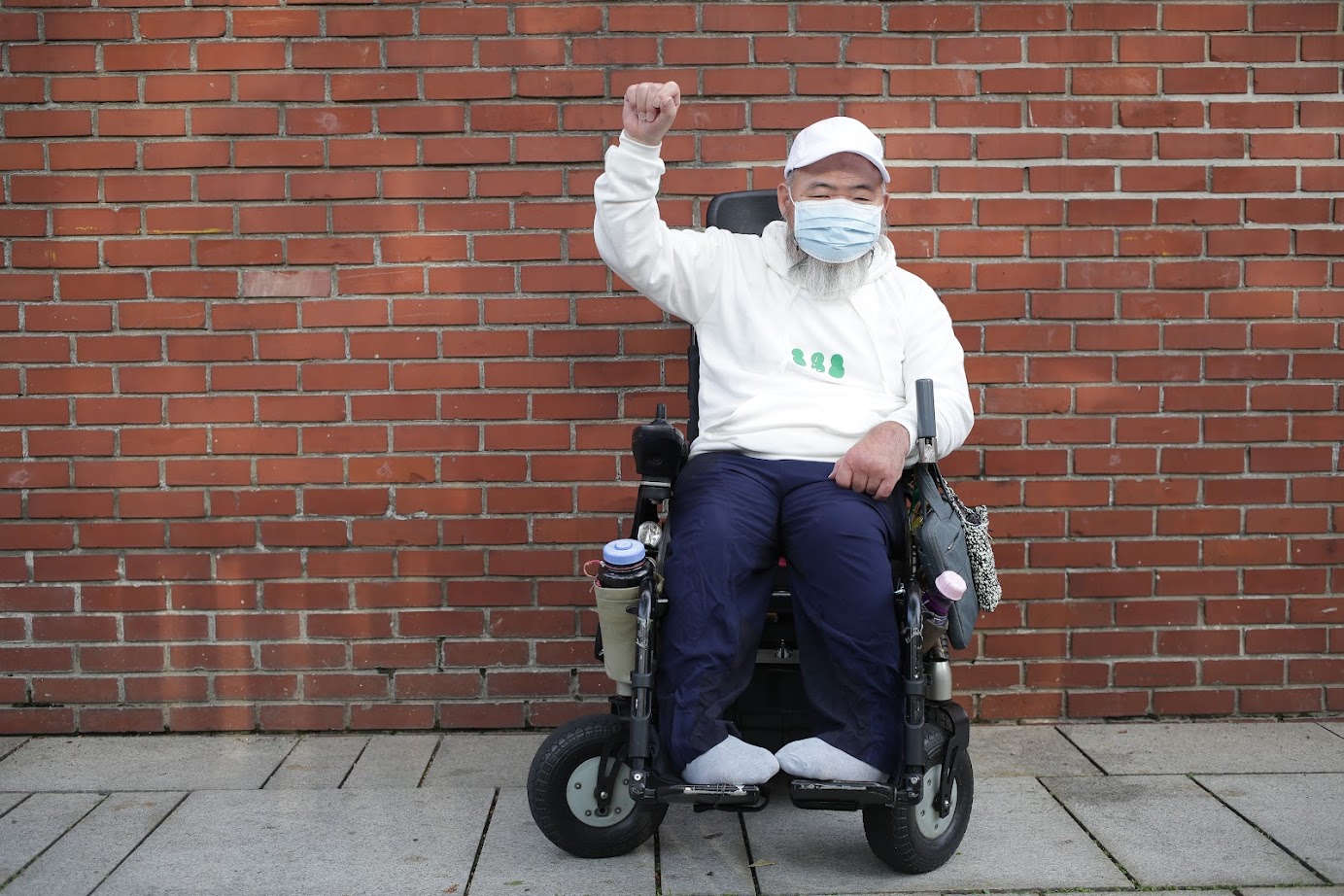녹색 눈사람(흰색 후드) 을 입고 휠체어에 앉아 투쟁포즈 (한손을 올린) 노들장애인야학 교장선생님