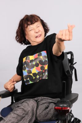 장애인지역공동체 티셔츠를 입고 손가락 하트를 보내는 활동가