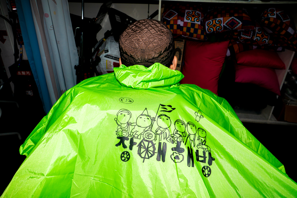 장애 해방 글씨가 대문짝 만하게 등판에 새겨진 판초 우비 초록색 뒷모습 클로즈업.