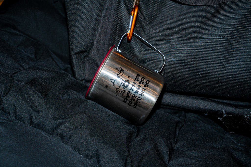 들다방 스테인리스 키링 컵 근접 사진. 검은 천 위에 스테인리스 은빛이 빛난다.