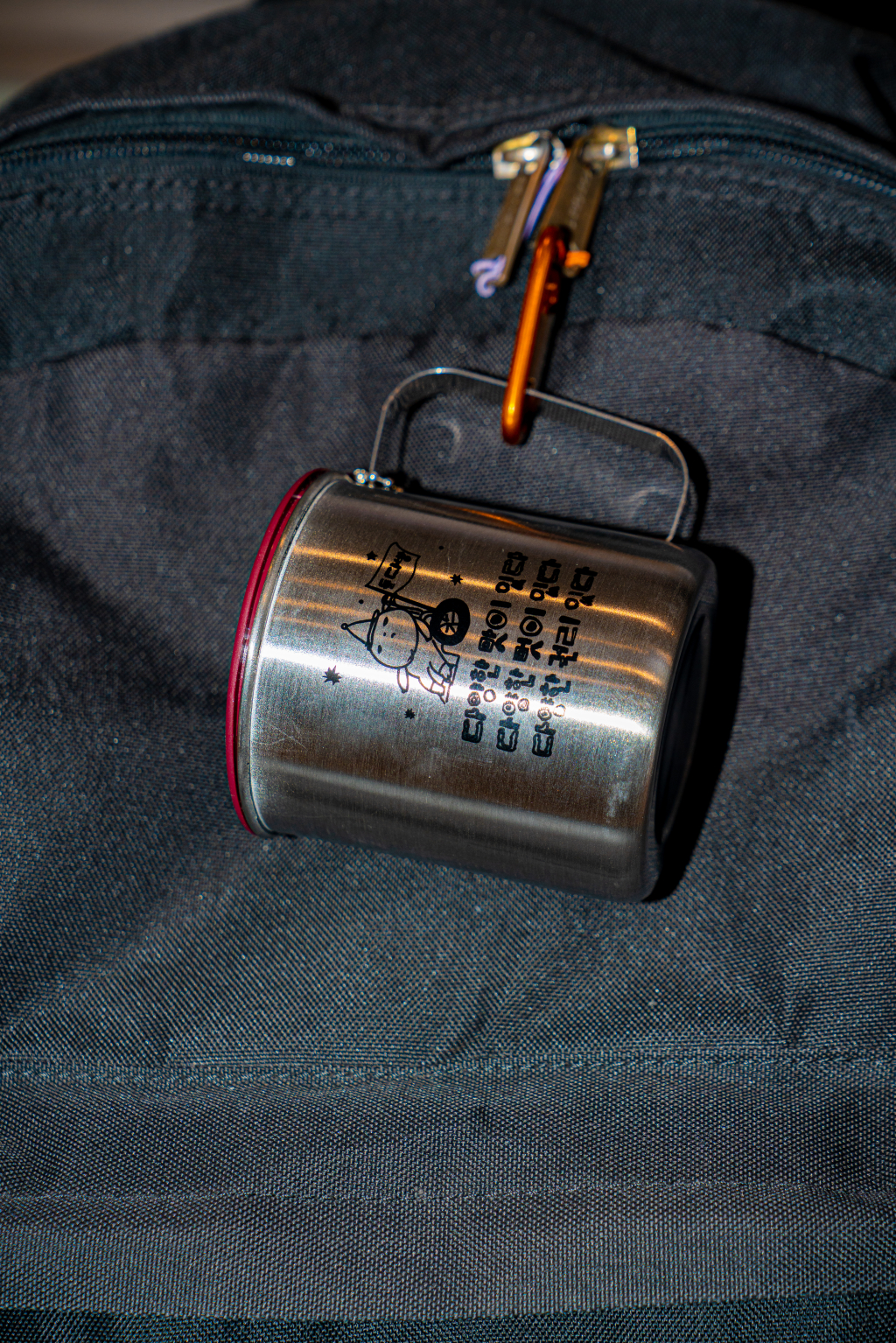 검은 가방에 매달린 들다방 스테인리스 키링 컵 근접 사진. 검은 가방의 끈 손잡이에 들다방 컵이 키링으로 매달려 있다.