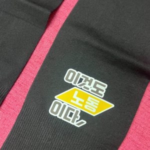 붉은색 배경아래 검정색 쿨토시의 풀샷 화면, 이것도 노동이다라고 한쪽에 프린트되어있다. 노동에 노란색 마름모